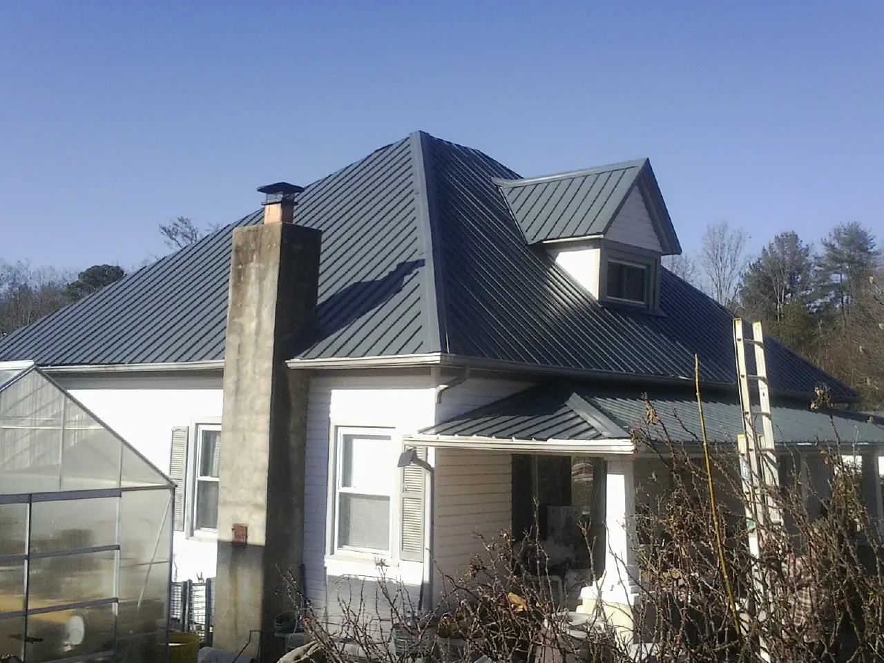 Dark blue standing seam metal roof on a white farmhouse with dormer — Slate & Tile Roof Repair by Roofing Brothers in Pierre Part