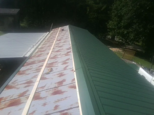 Old rusted panels beside newly installed green metal roofing — Wind Damage Roof Repair by Roofing Brothers in Pierre Part