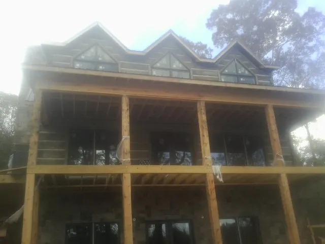 Dormers and porch framing on a large log home under construction — Roof Coating work by our crew in Pierre Part