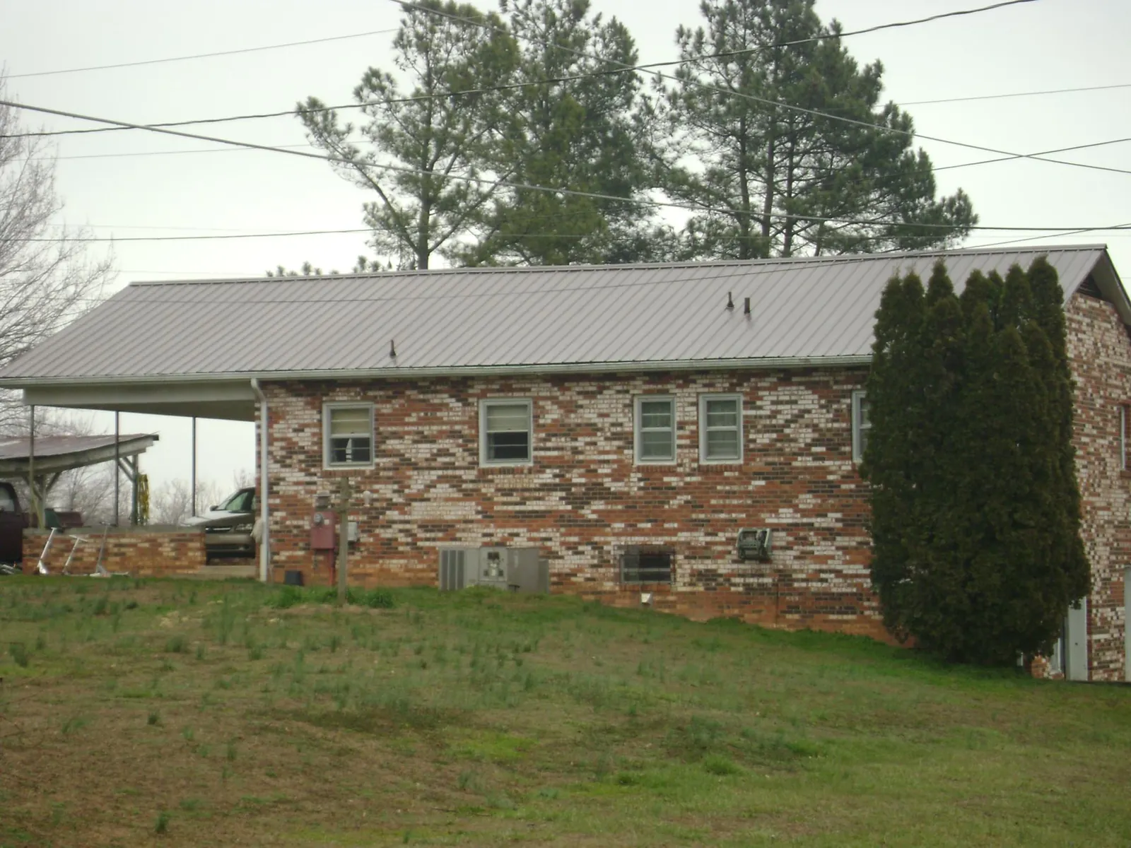 Gray metal roof on a brick split level home with a carport in Pierre Part