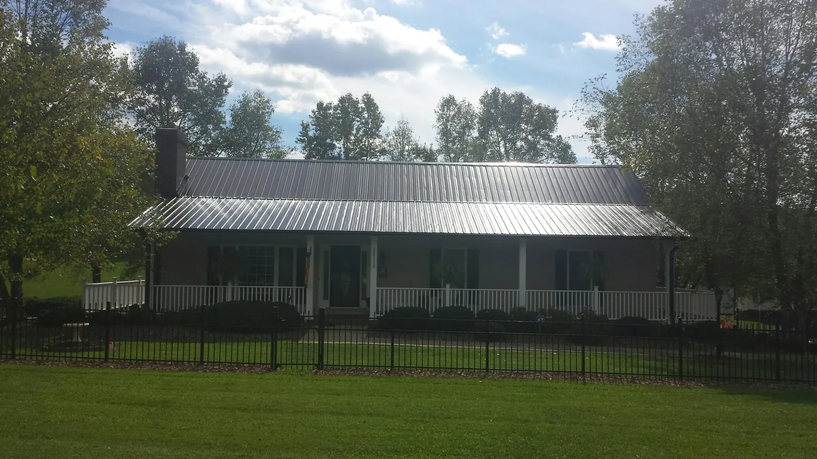 Gray metal roof on a brick ranch with a full width front porch — Gutter Guard Installation work by our crew in Pierre Part