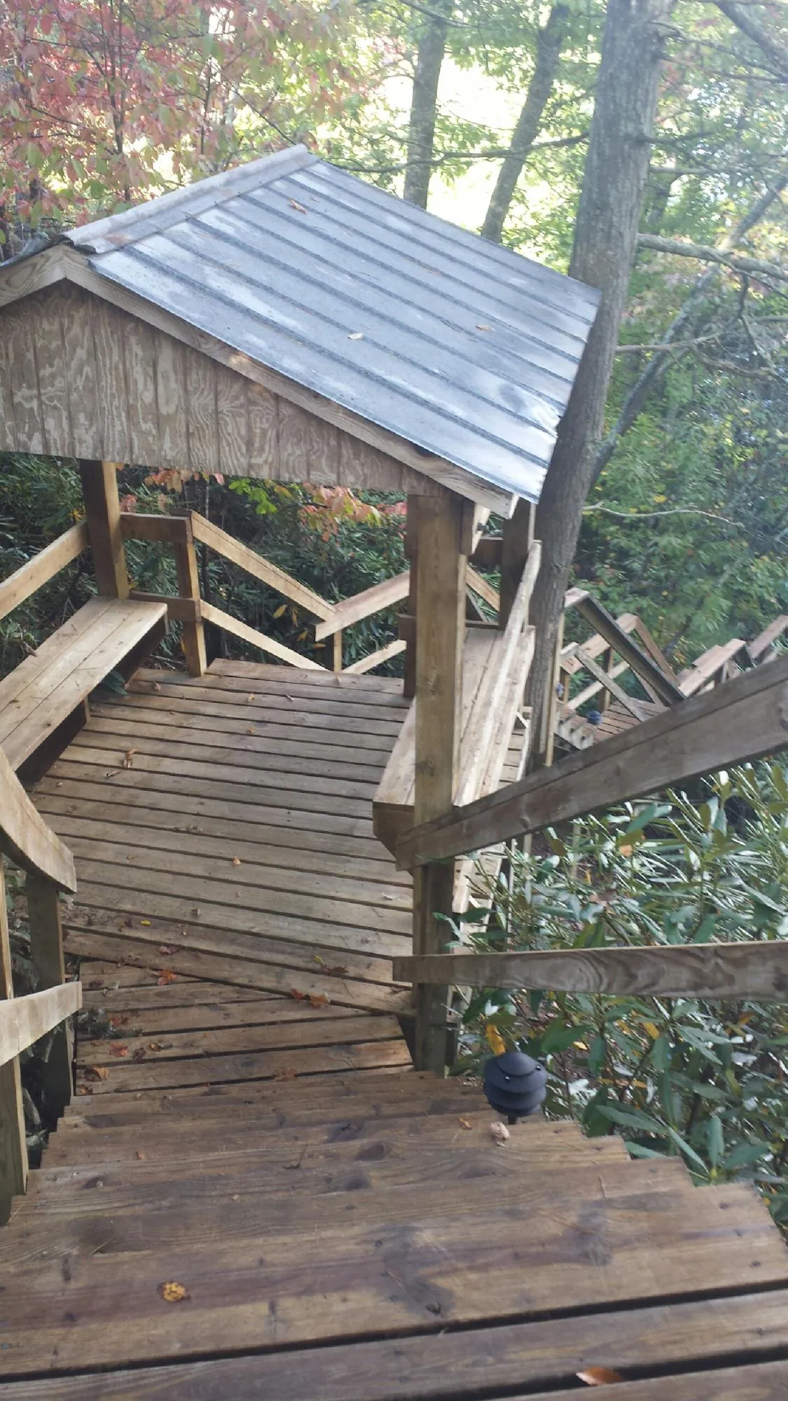 Metal roofed shelter over wooden steps on a wooded walkway — Skylight Repair & Installation work by our crew in Pierre Part