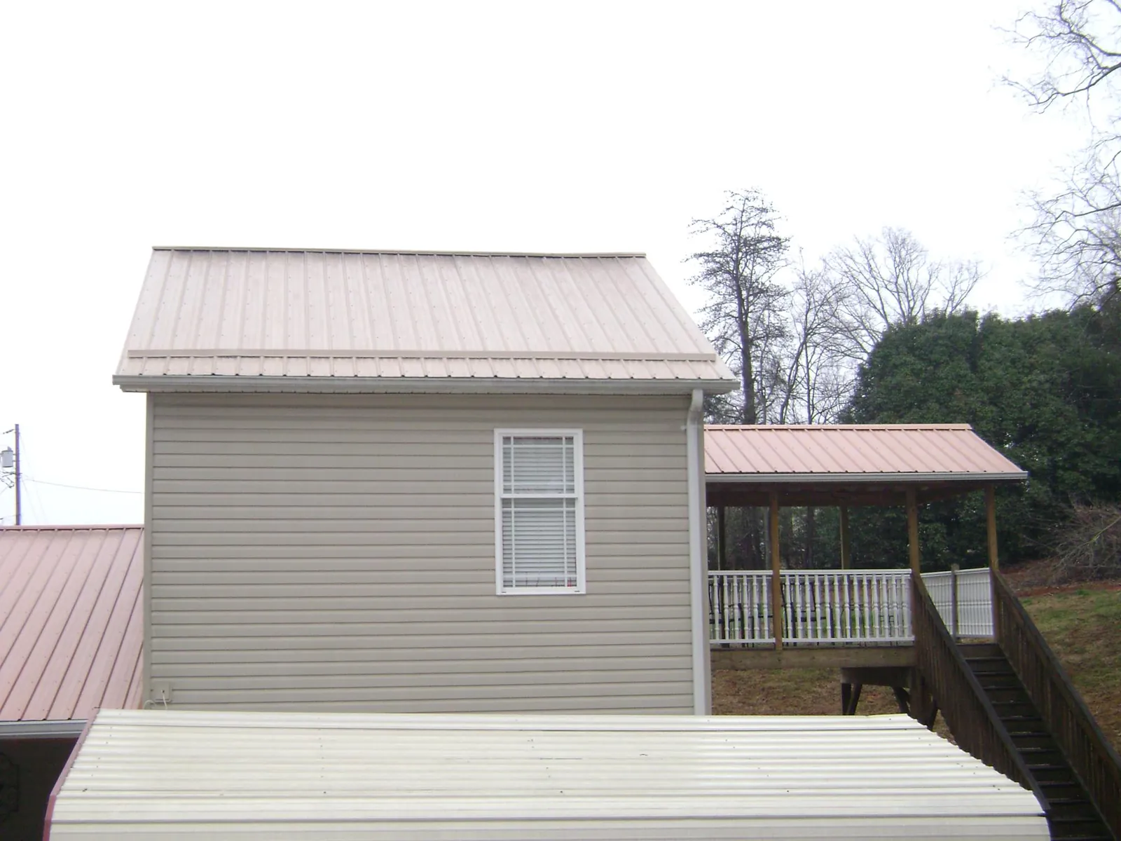 Tan metal roofs on a two story addition and attached porch, from a Roof Replacement job in Pierre Part